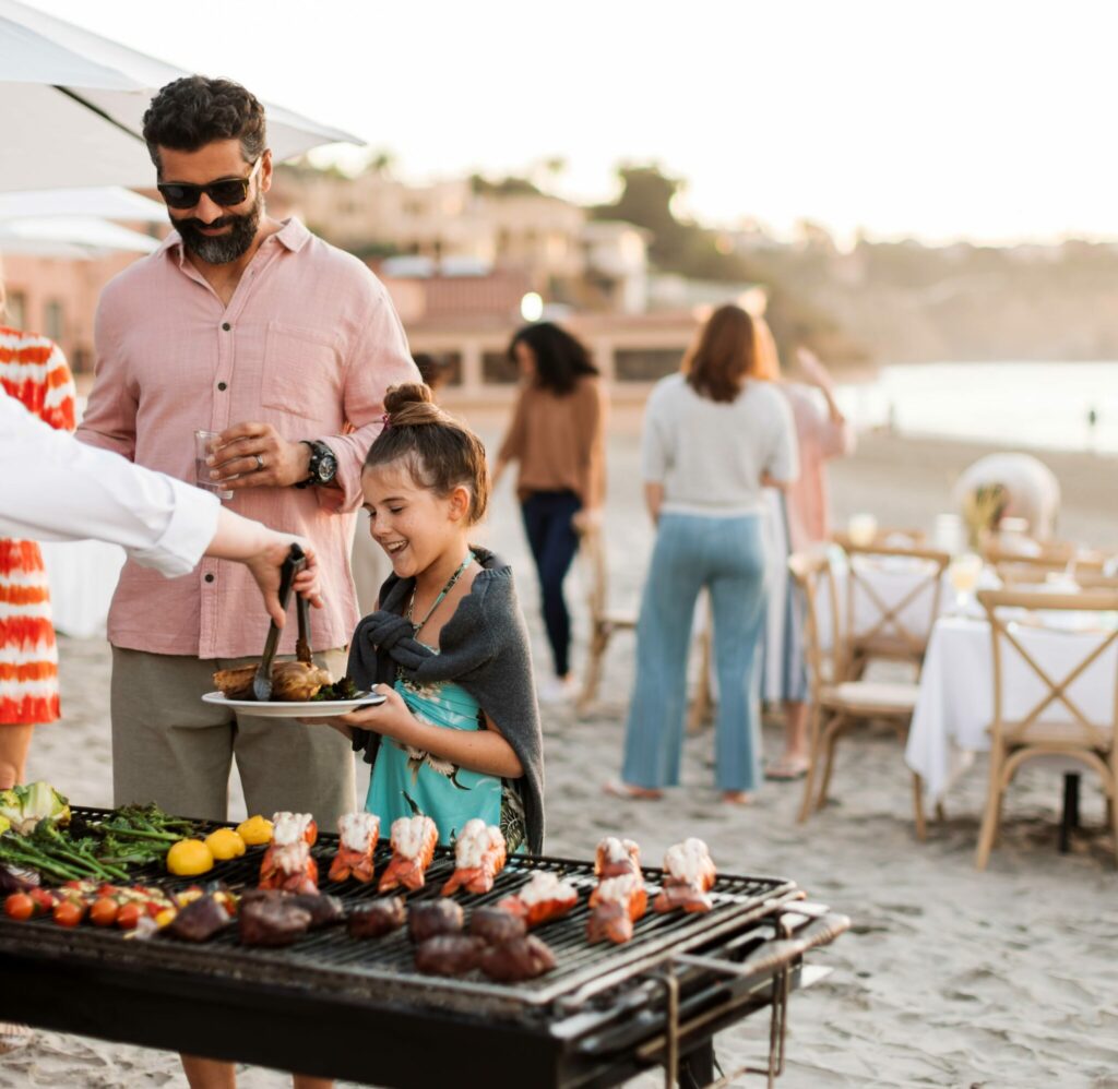 A family being served food at a reception on the beach at La Jolla Beach & Tennis Club